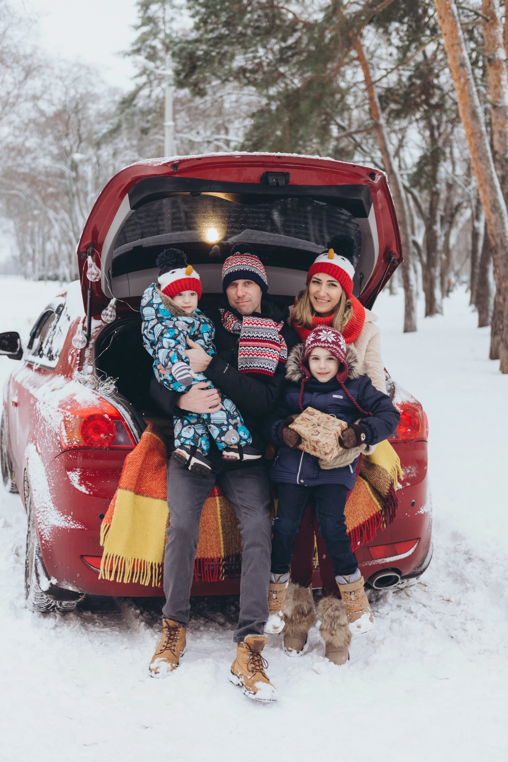 Щаслива сім'я на зимовому фоні з машиною та лісом.