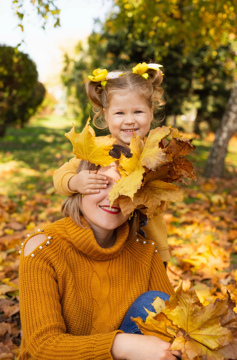 Мама та дочка весело граються з осіннім кленовим листям у лісі Кременчука.