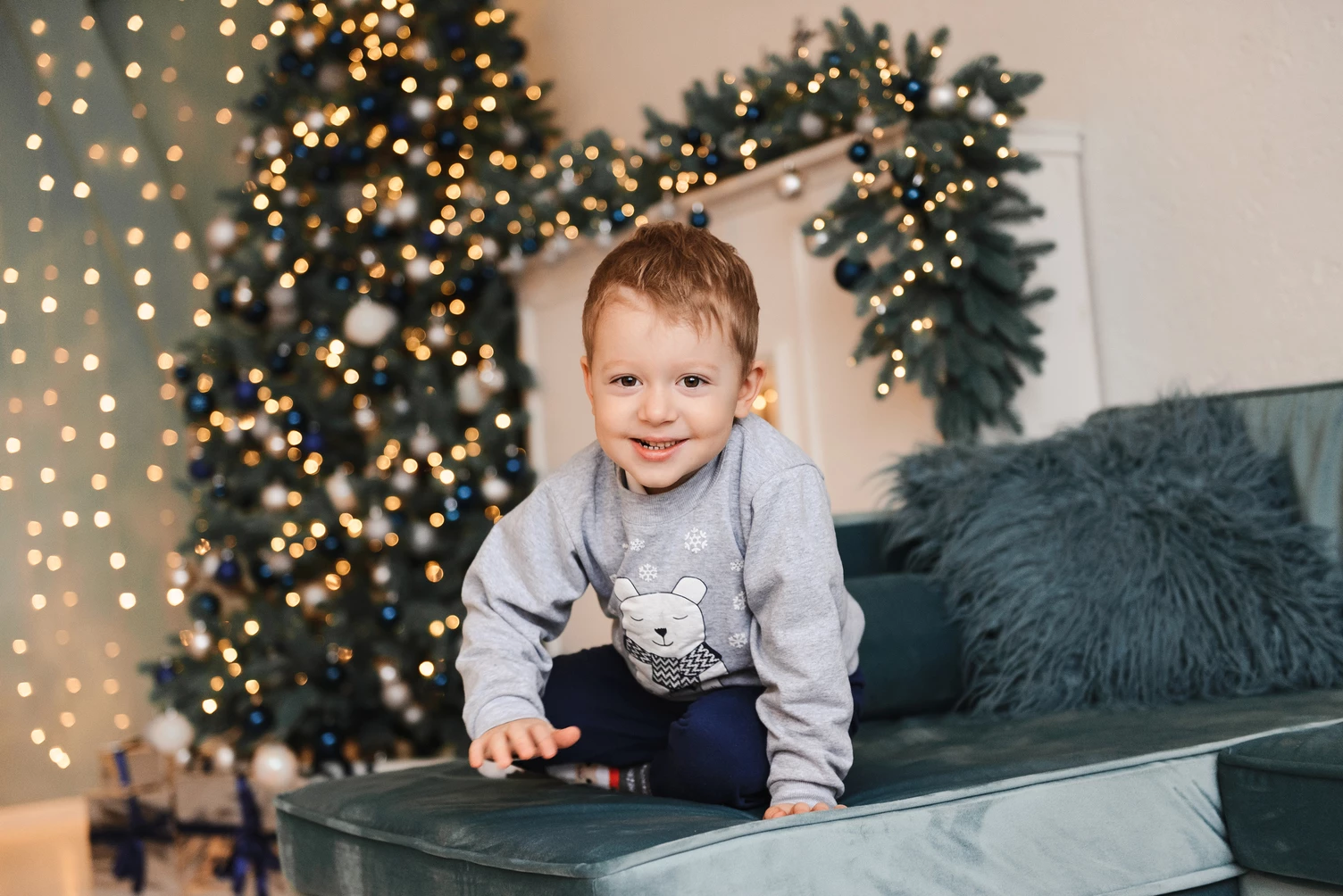 Портрет дитини з новорічною ялинкою та гірляндою на задньому плані.
