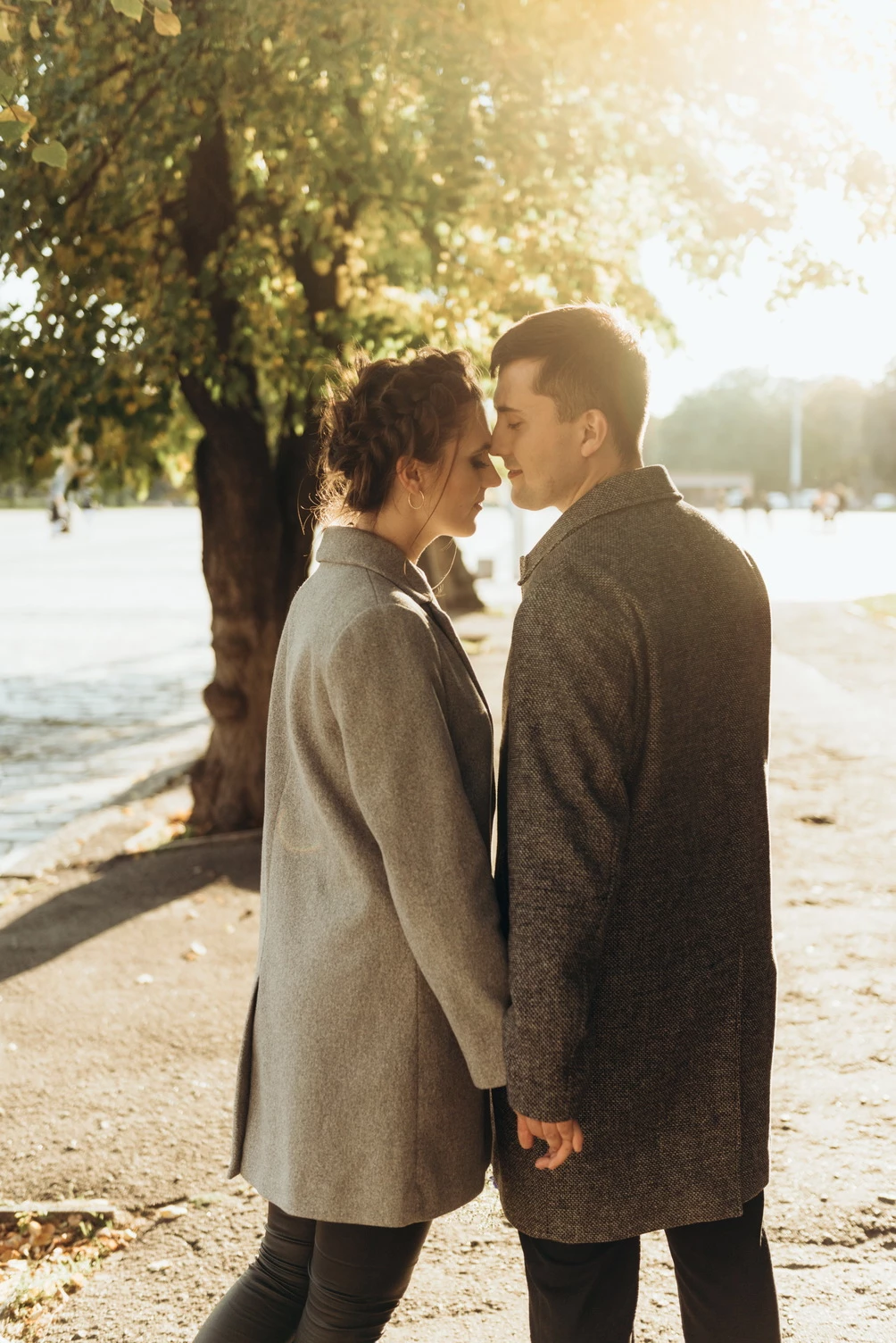 Романтична сцена в Кременчуці: пара стоїть близько під деревом, дивлячись одне на одного і тримаючись за руки.