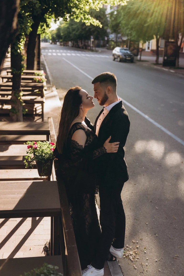 Закохана пара з Кременчука обмінюється поцілунками під теплими сонячними променями на фотосесії біля квітів.