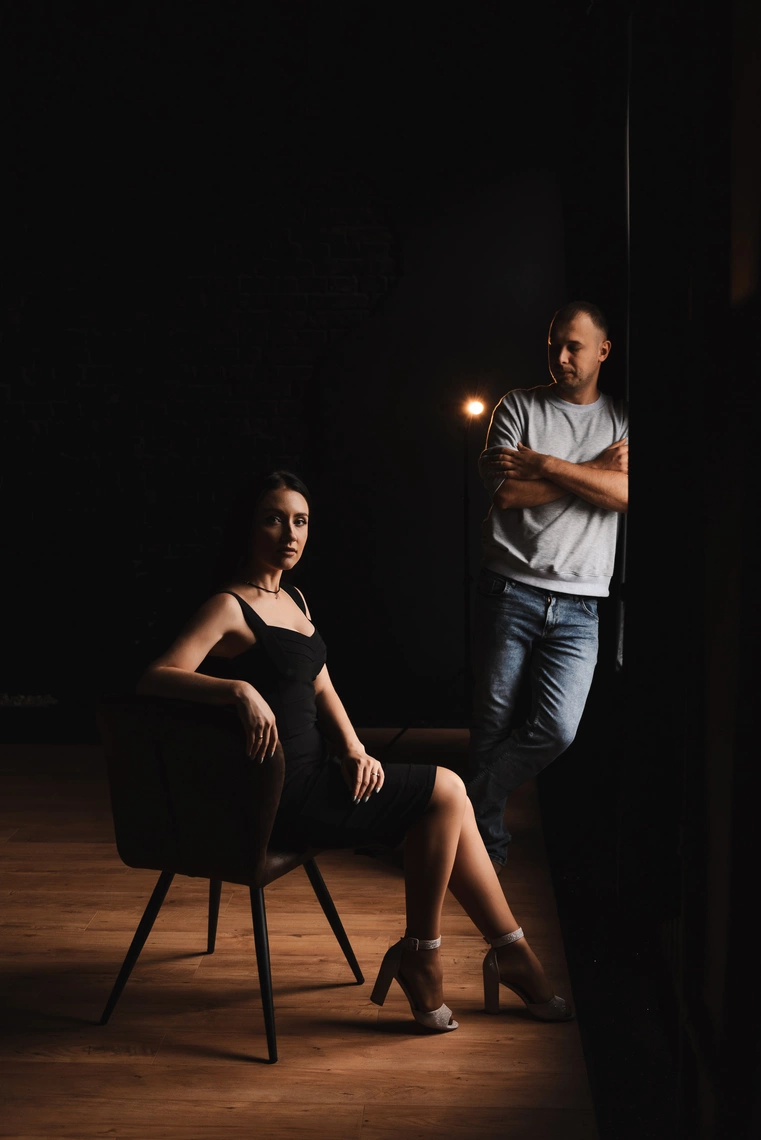 Драматичний портрет закоханої пари у темній кімнаті з чаруючим освітленням із вікна.