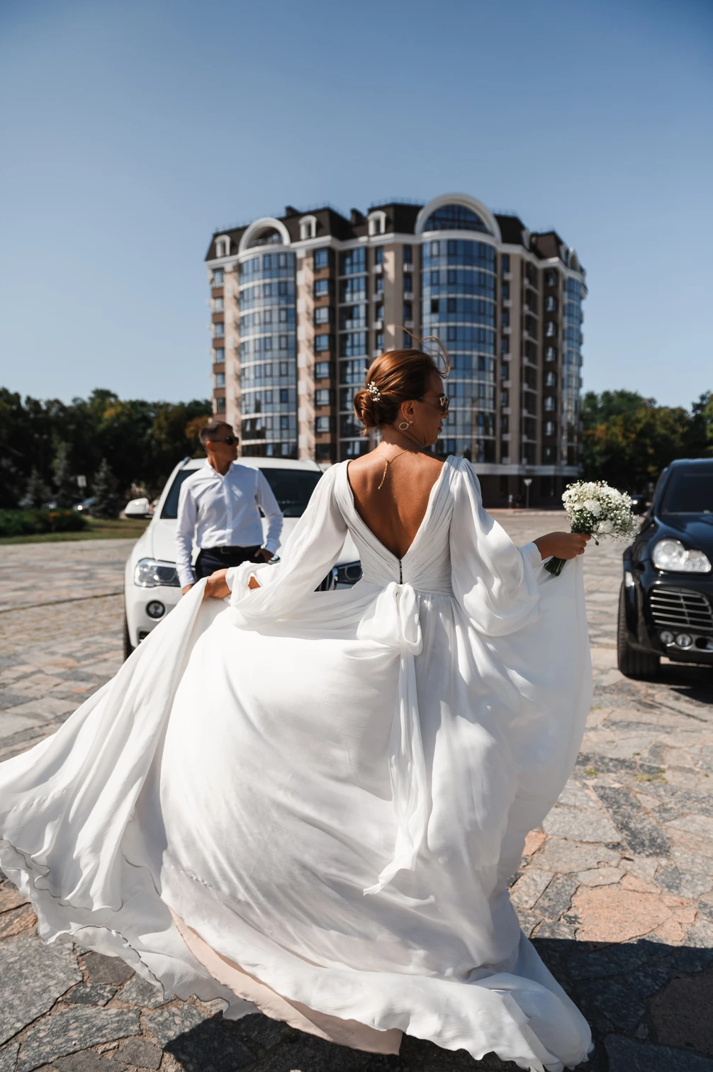 Наречена в білій сукні біжить зі своїм весільним платтям на фоні новобудови в Кременчуці