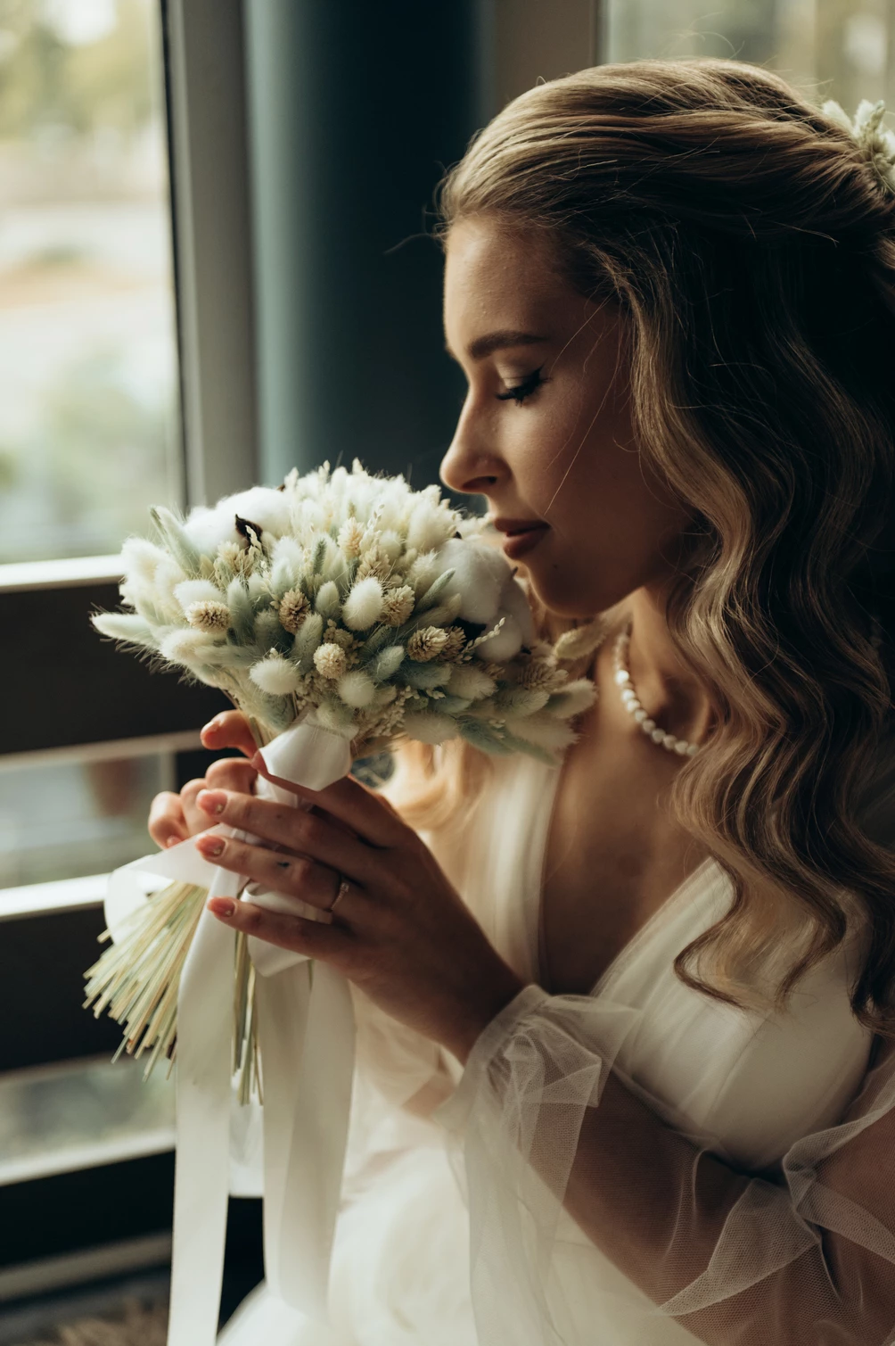 Елегантна наречена з весільним букетом у м'якому світлі, створюючи неповторний образ романтичного весільного дня.
